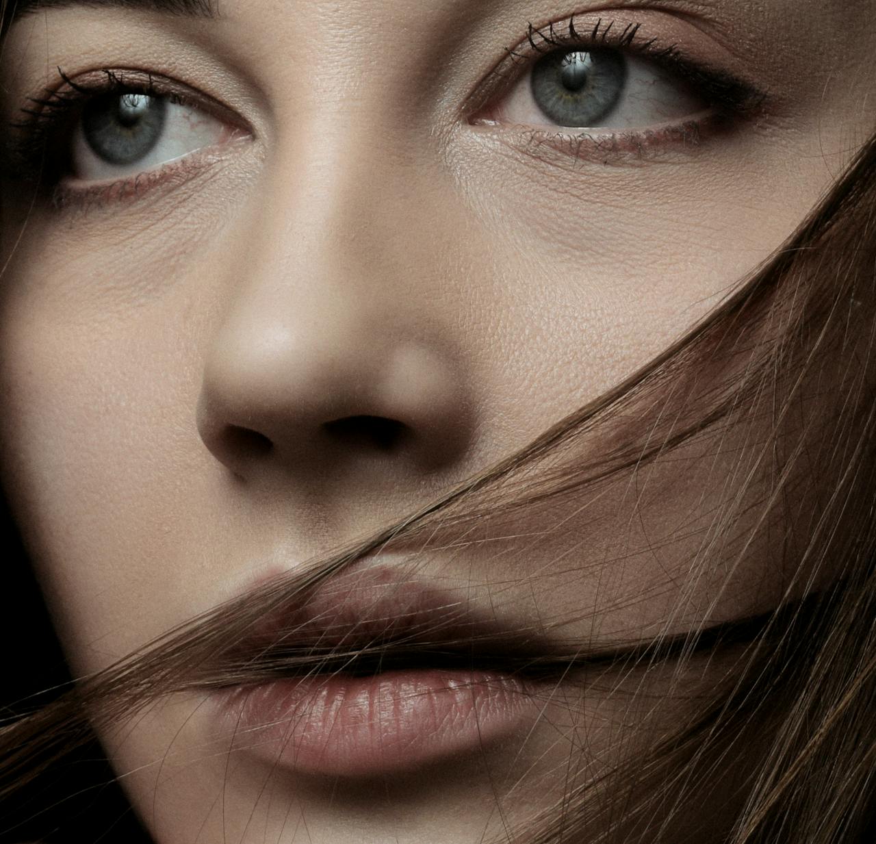 A detailed close-up portrait of a woman with piercing eyes and wind-swept hair.