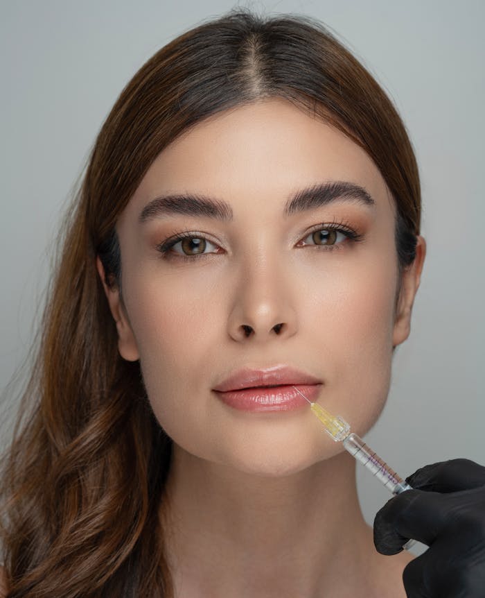 Woman receiving a cosmetic lip injection by a professional in a clinical setting.
