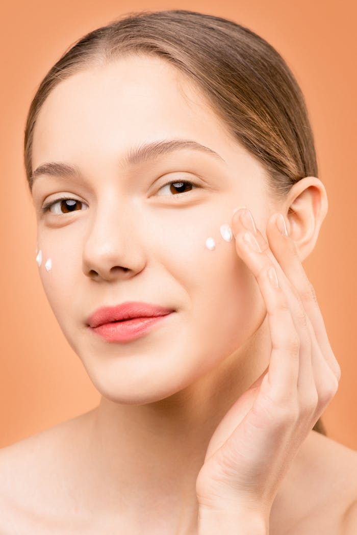 Young woman applying facial cream for healthy skincare routine.