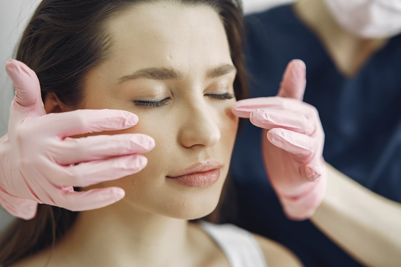 Close-up of a woman with eyes closed receiving facial care in a beauty clinic indoors.